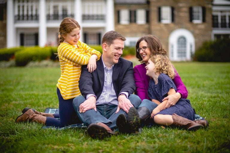 A family sits on a blanket in front of Glenview Mansion.