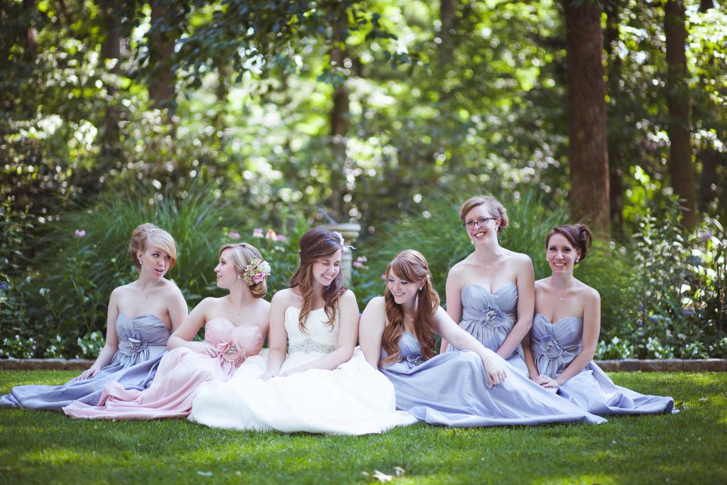 A group of bridesmaids sitting on the grass at Gramercy Mansion in Stevenson, Maryland.