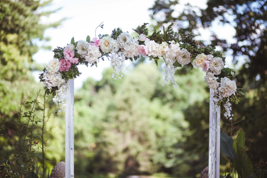 A white wedding arch adorned with pink and white flowers set in Stevenson, Maryland at the Gramercy Mansion.