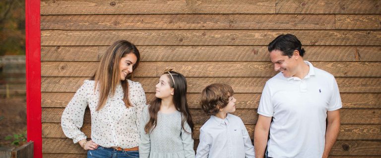 A family is posing in front of a red barn in Maryland.