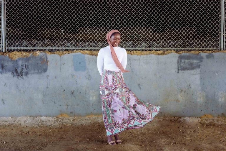 A woman in a pink skirt standing in front of a fence at Jonas and Anne Catharine Green Park in Annapolis, Maryland.