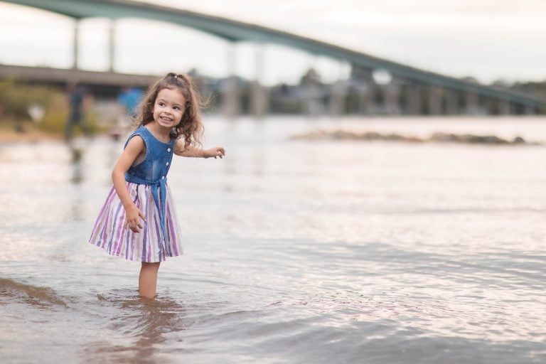 A little girl standing in the water near a bridge in Annapolis, Maryland.