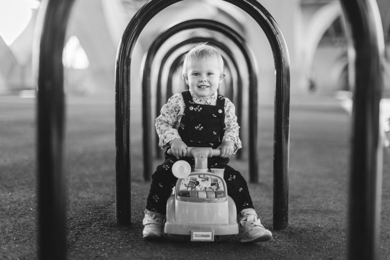 A black and white photo of a little girl in a toy car taken in Jones Point Park, Virginia.