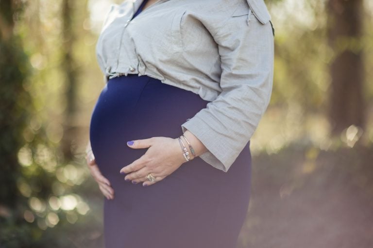 A pregnant woman in a blue dress is standing in Jones Point Park.