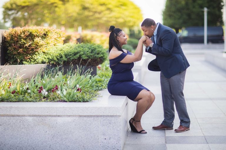 A couple kissing on a bench in front of the Kennedy Center Grounds building in Washington DC.