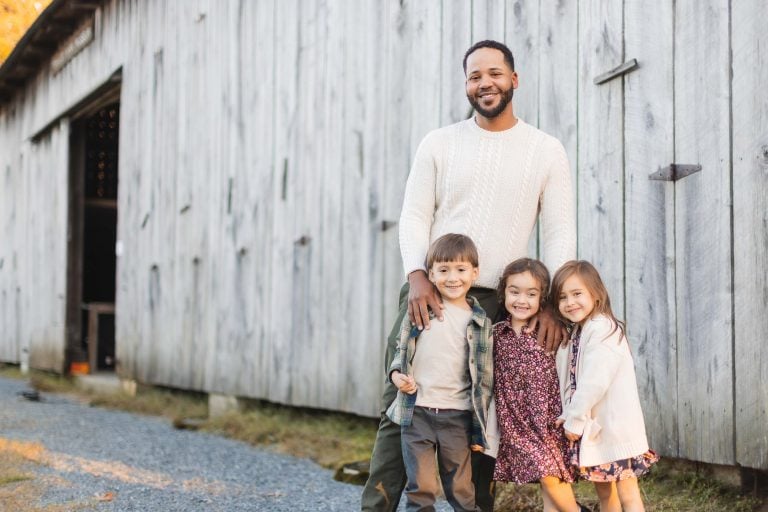 A man and his children standing in front of a barn at Kinder Farm Park.