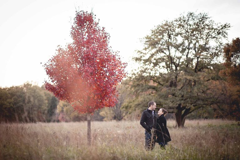 A couple standing in the National Arboretum with a red tree in the background.