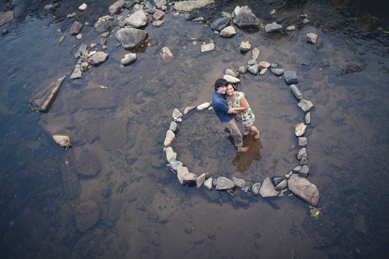 A couple is standing in a circle of rocks in the river at Old Ellicott City, Maryland.