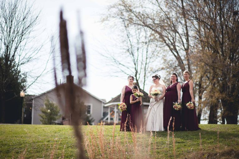 A group of bridesmaids in burgundy dresses standing in front of Manor at Silo Falls in Brookeville, Maryland.