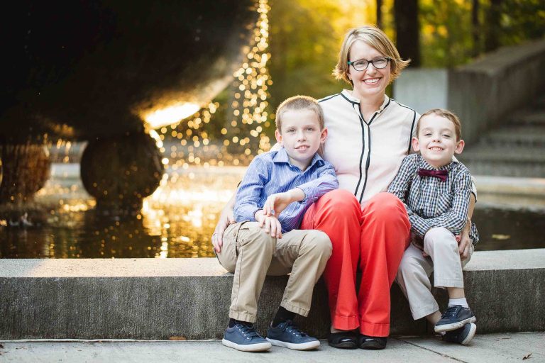 A woman and two boys sitting on steps in front of a fountain at Theodore Roosevelt Island.