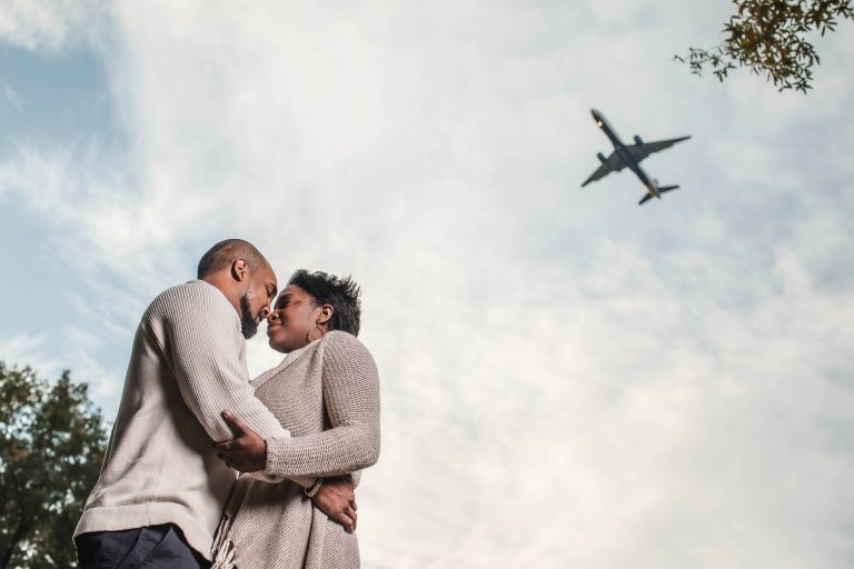 A couple embracing in front of a plane in the sky in Arlington.