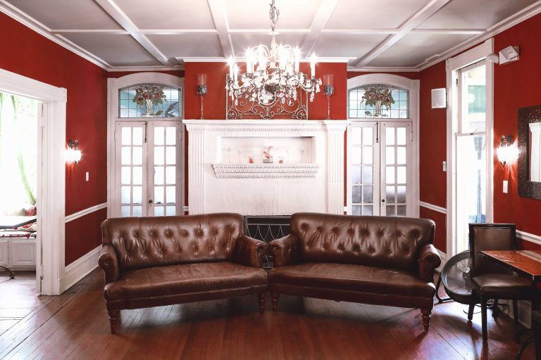 A living room with two leather couches and a chandelier located in Havre de Grace, Maryland at the Vandiver Inn.