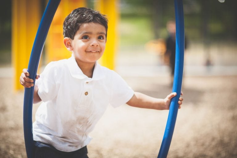 A young boy playing with a blue hoop at Wheaton Regional Park in Maryland.