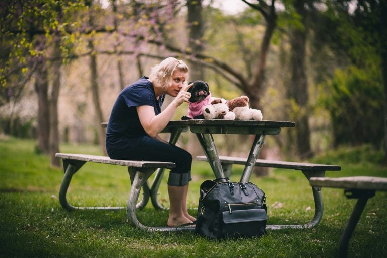 A woman sits at a picnic table in Wheaton Regional Park with two stuffed animals.