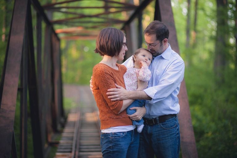 A man and woman standing on a wooden bridge with a baby in Wheaton, Maryland.