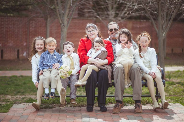 A family sits on a bench in front of a brick wall at Acton's Cove Waterfront Park in Maryland.