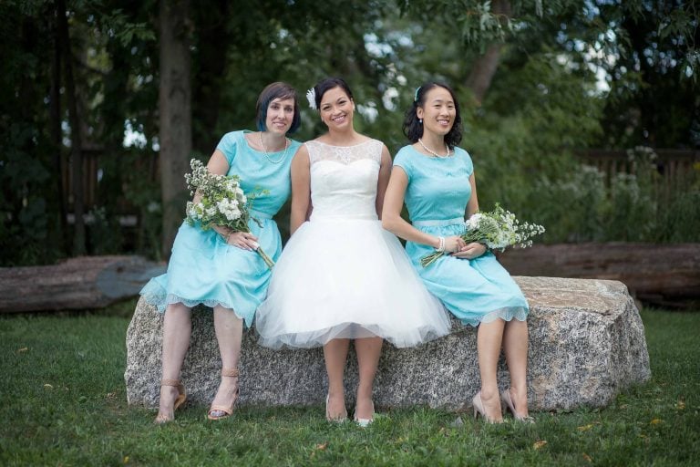 Three bridesmaids posing on a large rock at Concord Point Park.