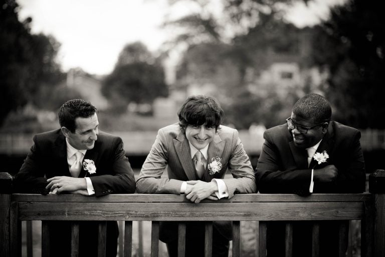 Three groomsmen leaning on a railing at Concord Point Park in Havre de Grace, Maryland.