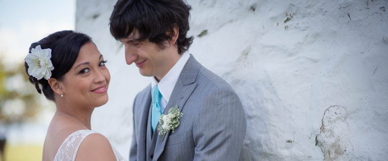 A bride and groom posing in front of a white wall at Concord Point Park, Havre de Grace, Maryland.