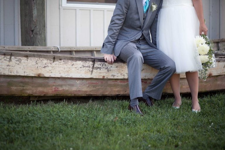 A bride and groom posing next to a boat at Concord Point Park in Havre de Grace, Maryland.