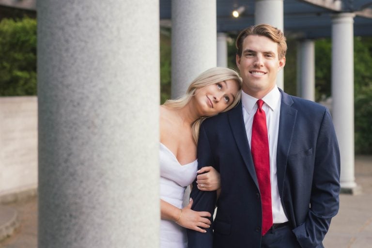 A bride and groom posing in front of the George Mason Memorial columns in Washington DC.