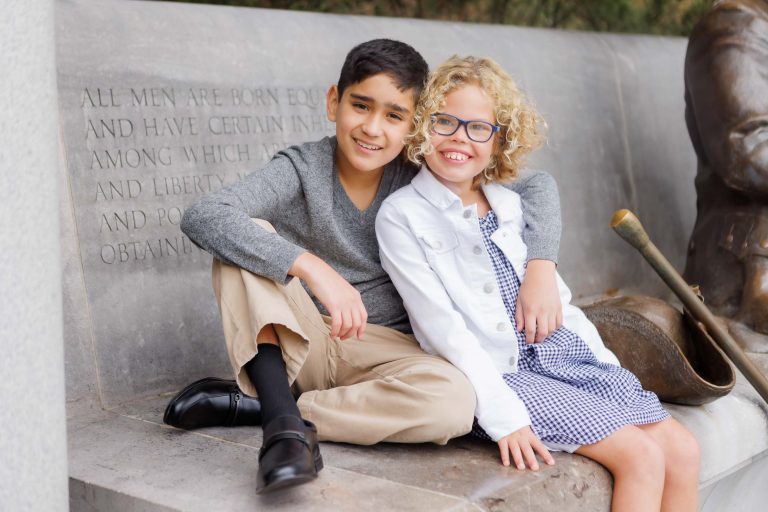 A boy and girl sitting on a bench next to the George Mason Memorial in Washington DC.