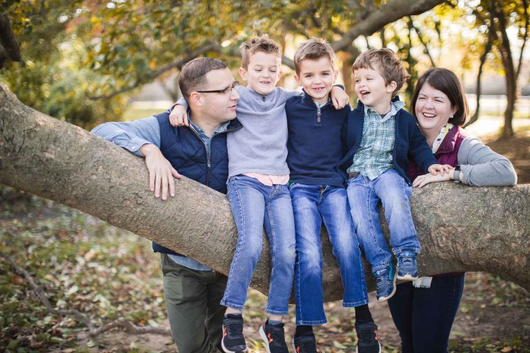 A family sits on a tree branch near the George Mason Memorial for a family photo in Washington DC.