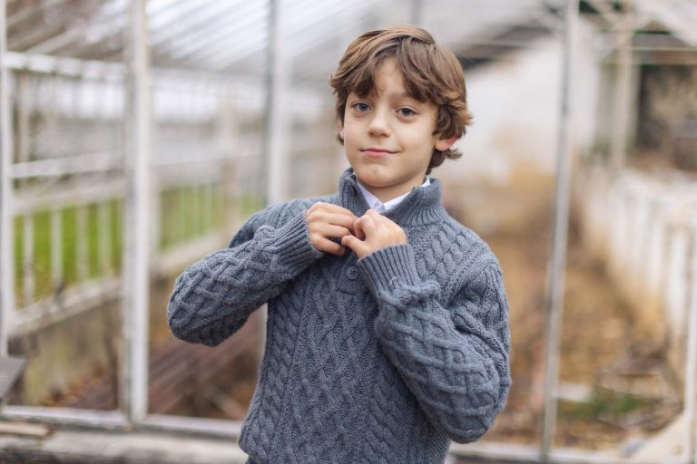 A young boy adjusting his tie in a greenhouse at Hampton Mansion.