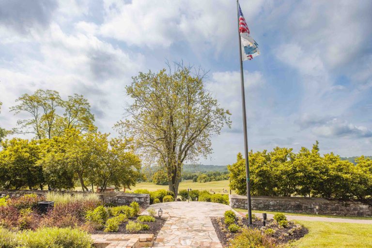 An american flag is flying in the middle of a grassy field at Hayfields Country Club.