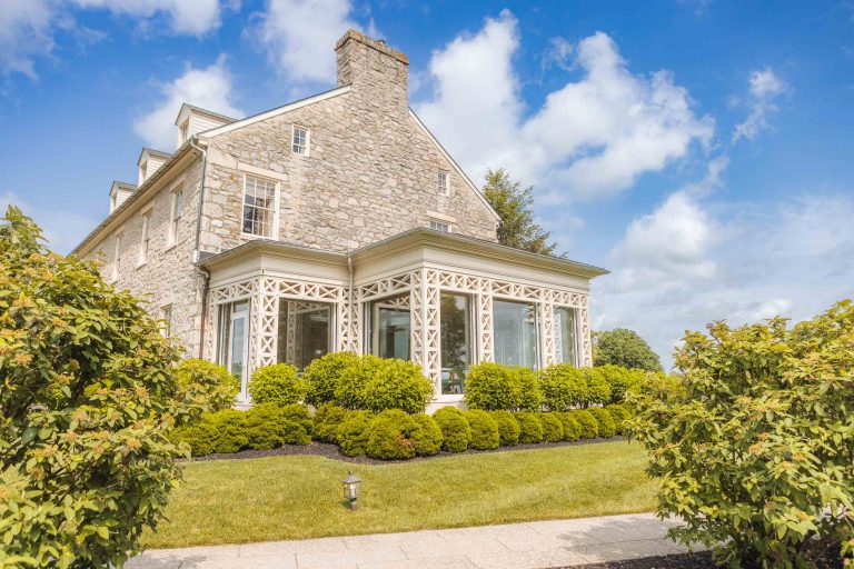 A stone house with a lawn and bushes located in Hunt Valley, Maryland.