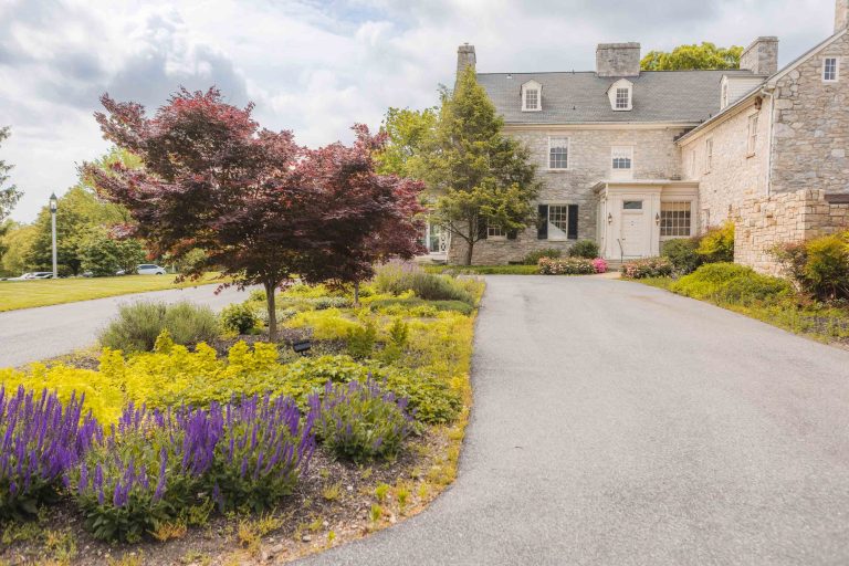 A stone house in Maryland with purple flowers in front of it.