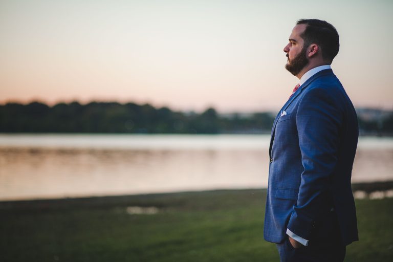 A man in a suit standing near the Jefferson Memorial at sunset in Washington DC.