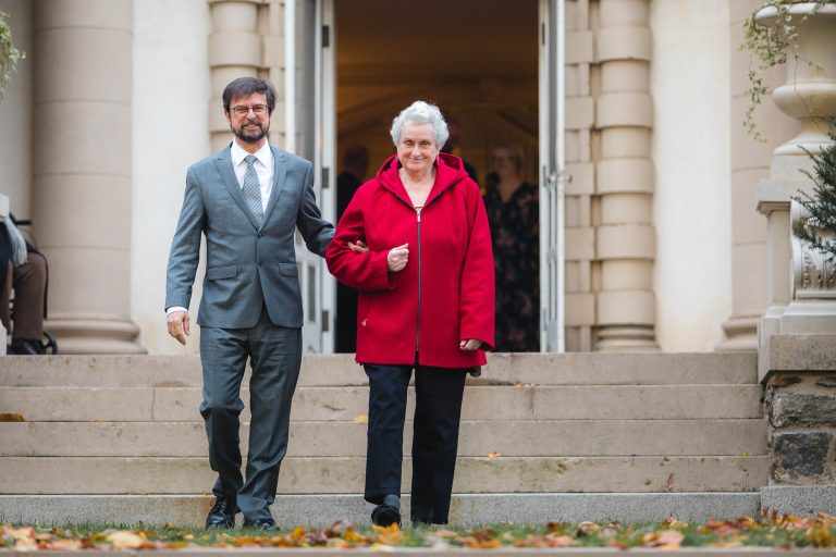 A couple in formal attire is descending the steps of Liriodendron Mansion in Bel Air, Maryland.