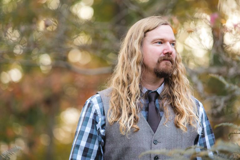 A man with long hair and a vest standing near Liriodendron Mansion in Bel Air, Maryland.