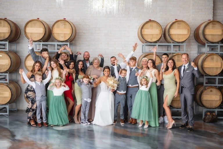 Wedding party posing in front of wine barrels at Two Lions Vineyard.