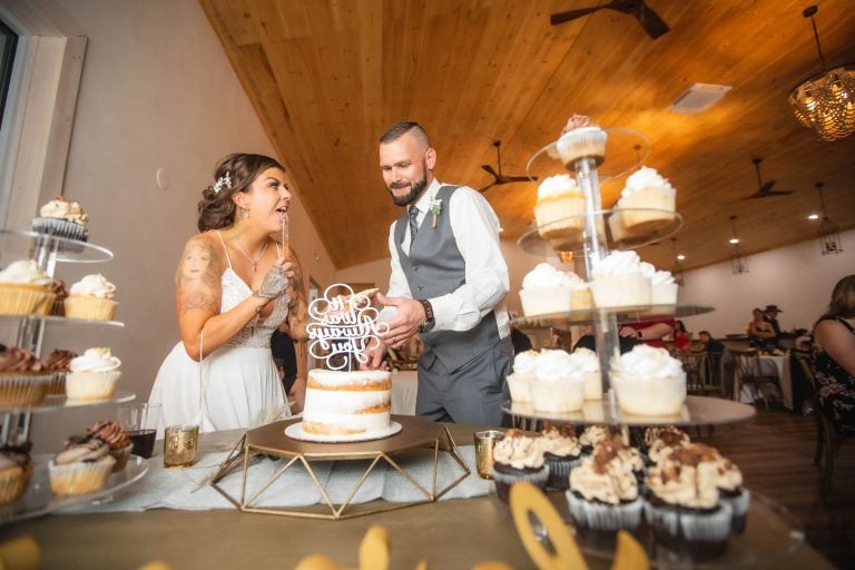 A bride and groom cutting their wedding cake in front of cupcakes at Two Lions Vineyard in Upper Marlboro, Maryland.