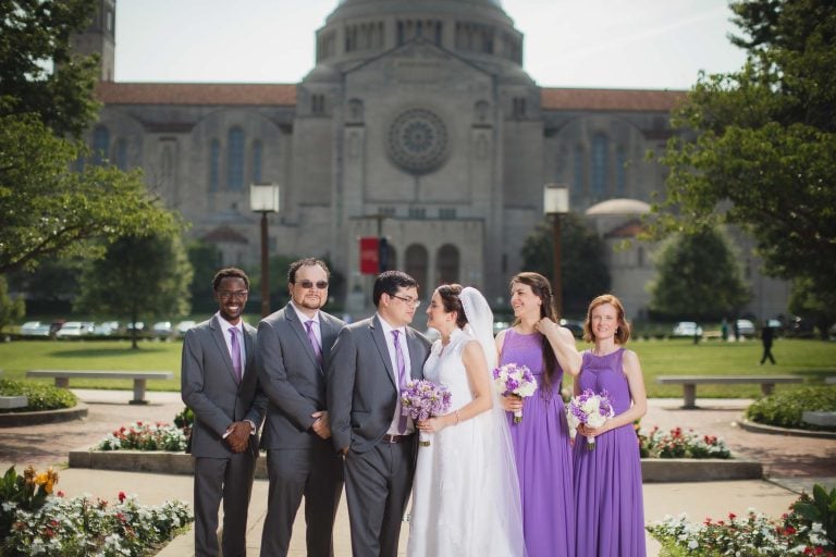 A group of bridesmaids and groomsmen posing in front of a cathedral in Washington DC.