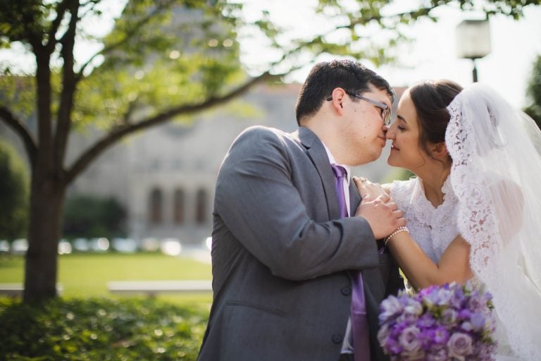 A bride and groom kissing in front of the Catholic University building in Washington DC.