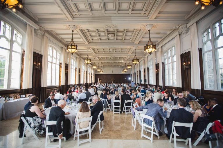 A group of people sitting at tables in a large hall at Catholic University in Washington DC.