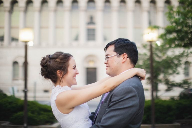 A bride and groom hugging in front of a Catholic University building in Washington DC.