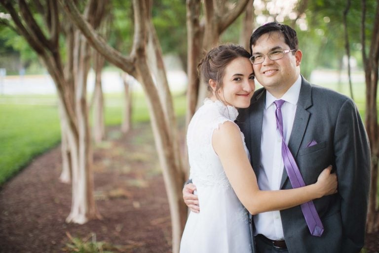 A bride and groom embracing in front of trees in Washington DC.