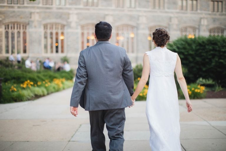 A bride and groom walking down a sidewalk in front of a building in Washington DC.