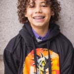 A young boy wearing a dragon ball hoodie poses for a portrait at the National Portraits Gallery with his family.