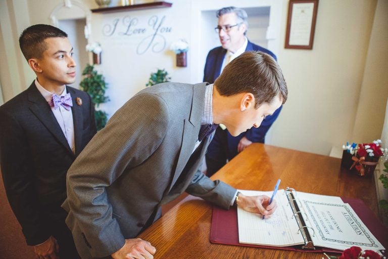 A man signing a document in front of a group of men at the Circuit Court for Anne Arundel County in Annapolis, Maryland.