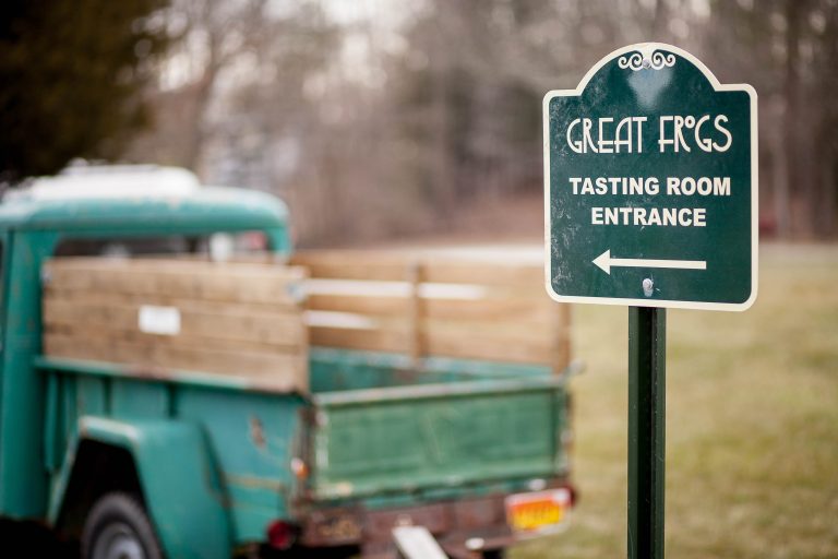 A green truck is parked next to a sign that says Great Frogs tasting room in Maryland, Annapolis.