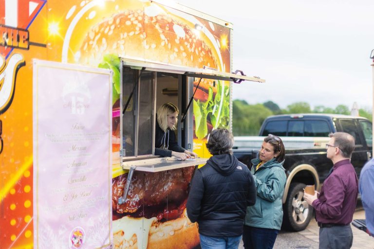 A group of people standing in front of a Great Frogs food truck in Maryland.