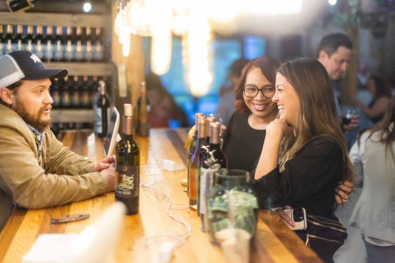 A group of people at a bar in Annapolis, Maryland talking about Great Frogs wine.