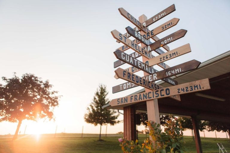 A wooden sign with directional arrows on it at Linganore Winecellars in Maryland at sunset.