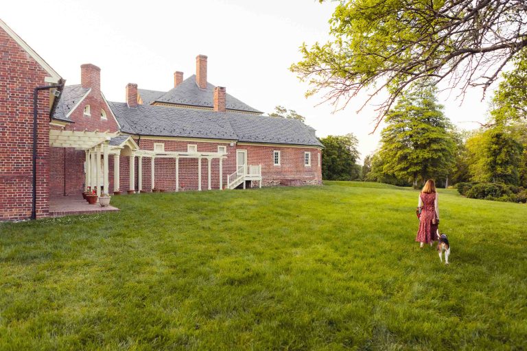 A woman walks her dog in front of Montpelier Mansion in Laurel, Maryland.