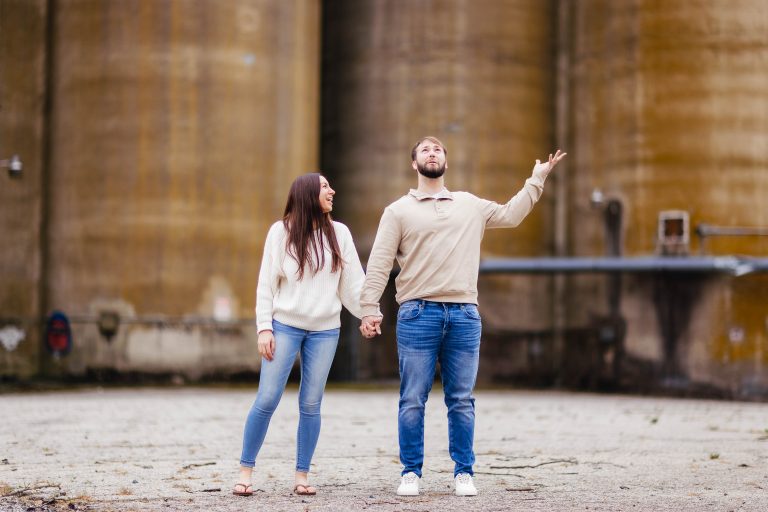 An engaged couple standing in front of a silo in Old Ellicott City, captured in a portrait-style engagement photo.